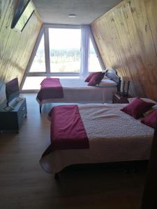 2 Betten in einem Zimmer mit einem großen Fenster in der Unterkunft CHALET LOS PINOS in Duitama