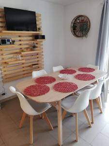 einen Esstisch mit weißen Stühlen und einen TV in der Unterkunft La Cigale du Pas du Ventoux en Provence in Mollans-sur-Ouvèze