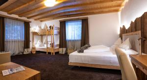 a bedroom with two beds and a table and a desk at Hotel Schmung in Alpe di Siusi