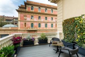 a balcony with plants and chairs and a building at The H'All Tailor Suite Roma in Rome