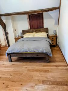 a bedroom with a bed and a wooden floor at The Old Granary Farm Cottage in Abergavenny