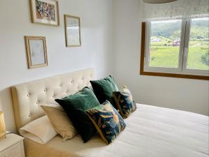1 dormitorio con cama con almohadas y ventana en Darou, en Vimianzo