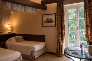 a bedroom with a bed and a table and a window at La Meridiana Hotel & Golf Resort in Garlenda