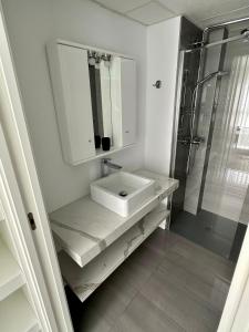 y baño blanco con lavabo y ducha. en PISO-DEL-PLAYA en Guardamar del Segura