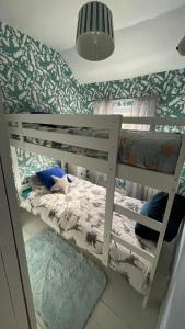a bedroom with two bunk beds with green wallpaper at Llanfair Caereinion house Quirky with river balcony in Llanfair Caereinion