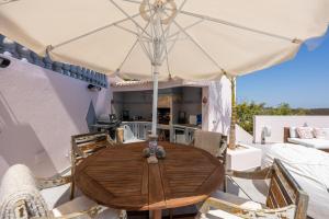 a wooden table with an umbrella on a patio at Luxurious & Famous Villa of Dutch TV Show in Budens