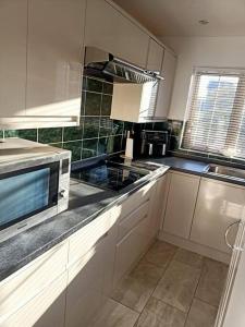 a kitchen with a microwave and a stove top oven at Lotus House in Needingworth