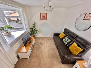 a living room with a black leather couch and a tv at Semi-detached 1-Bedroom Chalet in Uddingston