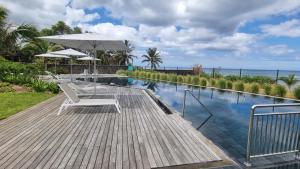 a swimming pool with a table and an umbrella at Ocean Point Beach Front Apartment in Pointe aux Piments