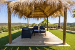 a wooden deck with chairs and a straw umbrella at Luxurious & Famous Villa of Dutch TV Show in Budens