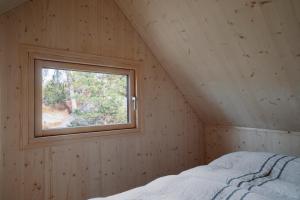 Cama en habitación de madera con ventana en Majamaja Helsinki off-grid retreat en Helsinki