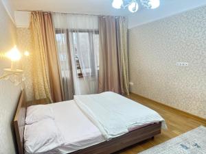 Habitación pequeña con cama y ventana en Двух комнатная квартира возле Арбат en Almaty