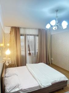 1 dormitorio con cama, lámpara de araña y ventana en Двух комнатная квартира возле Арбат en Almaty
