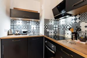 a kitchen with black cabinets and black and white tiles at Road to Disney by Plaza in Montévrain