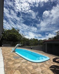 a blue swimming pool with a chair in a yard at Chácara Recanto da Paz in Caldas Novas