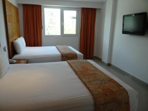 a hotel room with two beds and a television at Hotel Suites Gaby in Cancún