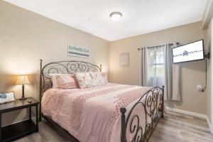 Un dormitorio con una cama grande con sábanas rosas y una ventana. en Downtown Branson Bungalow, en Branson