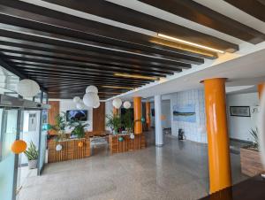 een kantoorlobby met oranje zuilen en een plafond met verlichting bij Les Ombrelles Appart'Hotel in Cotonou