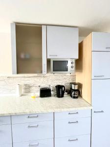 a kitchen with white cabinets and a microwave at Ferienwohnung für 5 Personen, gemütlich und möbliert in Stein