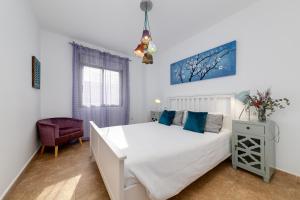 een slaapkamer met een wit bed en een blauw schilderij aan de muur bij Mi Patio in Torrevieja