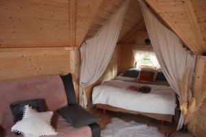 sypialnia z łóżkiem i kanapą w pokoju w obiekcie Cabane dans un jardin arboré w mieście LʼAbsie