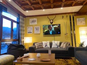 a living room with a couch and a tv on a wall at Vistas del Toneo in Puebla de Lillo