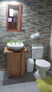 a bathroom with a sink and a toilet and a mirror at Cabañas la Estrella in Neltume