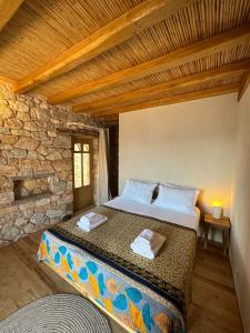 1 dormitorio con cama y pared de piedra en Phisis Nature Retreat, en Donoussa