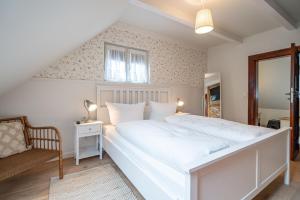 a bedroom with a large white bed and a chair at Altes Tagelöhner Haus - Whg 1 in Pudagla