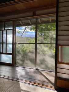 an empty room with a large window on a porch at KOMINKA guest house in Omachi