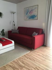 a living room with a red couch and a ottoman at Ferienwohnung Eisele in Buchenberg