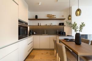 a kitchen with white cabinets and a wooden table at Beachhouse Bansin App 06 in Bansin