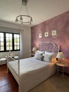 a bedroom with a white bed with a purple wall at Habitación Dache Lanzarote in Tías
