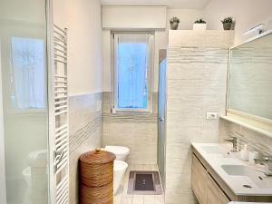 a bathroom with a toilet and a sink and a window at Casa Francesca Malpensa Milano in Busto Arsizio +23 photos
