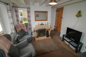 a living room with a fireplace and a tv at Greenside Cottage Caldbeck in Caldbeck