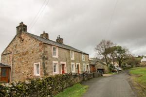 an old brick house with a stone wall at Greenside Cottage Caldbeck in Caldbeck