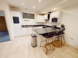 a kitchen with white cabinets and a black counter top at Newcastle Quayside - Sleeps 8 - Central Location - Parking Space Included in Newcastle upon Tyne
