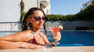 BERRY BELLA HOTEL في مرماريس: وجود امرأة في مسبح تحمل مشروب