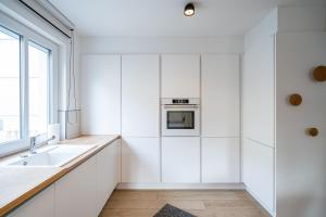d'une cuisine avec des placards blancs, un évier et une fenêtre. dans l'établissement Domizil Duene 8 App 3, à Ahlbeck