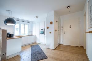 - une cuisine avec des placards blancs et un tapis au sol dans l'établissement Domizil Duene 8 App 3, à Ahlbeck