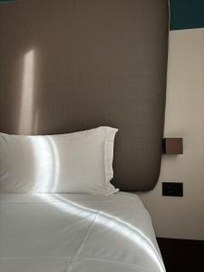 a bed with white sheets and pillows in a room at AV Hotel Milano in Milan