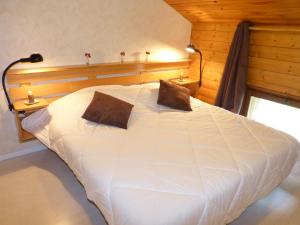 a bedroom with a large white bed with two pillows at Lou R'bat Pays in Le Grand-Bornand