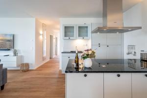 eine Küche mit weißen Schränken und einer schwarzen Arbeitsplatte in der Unterkunft Domizil Meerzeit, App. 7 in Ahlbeck + 17 Fotos