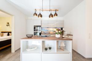 een keuken met witte kasten en een bar met bloemen bij Domizil Meerzeit App 6 in Ahlbeck