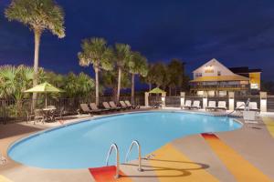 a large swimming pool with chairs and palm trees at Surfside Beach Oceanfront Hotel in Myrtle Beach