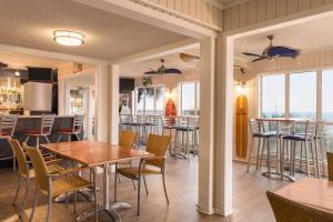 a dining room with tables and chairs and windows at Surfside Beach Oceanfront Hotel in Myrtle Beach