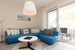 ein Wohnzimmer mit einem blauen Sofa und einem Tisch in der Unterkunft Dünenresidenz Heringsdorf, App. 12 in Bansin