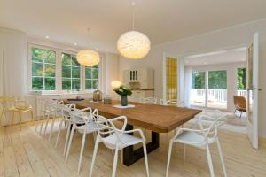 een eetkamer met een houten tafel en witte stoelen bij Ferienhaus Adlerhorst in Bansin