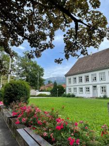 a white house with pink flowers in the yard at Gasthof Herzogstand bei Stefan in Benediktbeuern