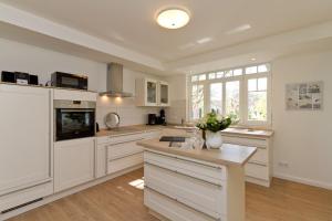 a large kitchen with white cabinets and a table at Ferienhaus Amelia Cottage in Neuhof